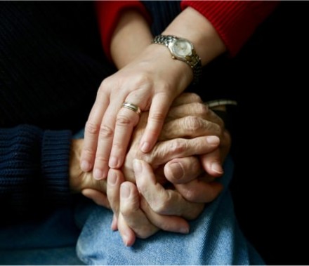 Artistically lit close-up photo of a wife lovingly clasping her husbands’ hands