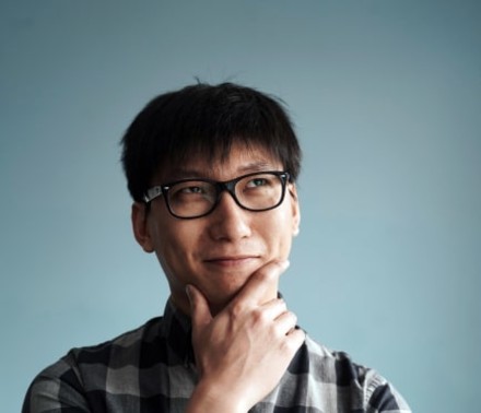 Naturally lit portrait of a biotech team member with glasses looking up and smirking playfully.